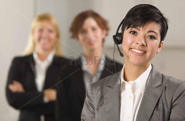 Pretty Hispanic Businesswoman with Colleagues Behind in an Office Setting.