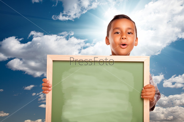 Proud Hispanic Boy Holding Blank Chalkboard Over Blue Sky and Clouds with Sun Burst.
