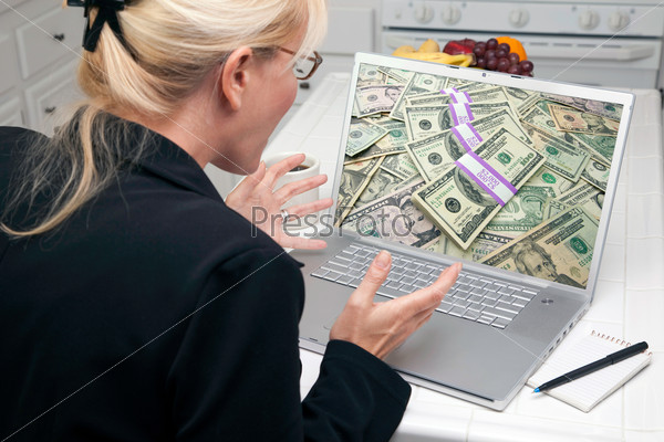 Excited Woman In Kitchen Using Laptop to Earn or Win Money