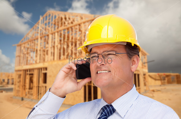 Contractor in Hardhat at Construction Site Talks on His Cell Phone, stock photo