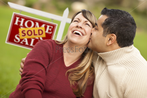 Happy Mixed Race Couple in Front of Sold Real Estate Sign.
