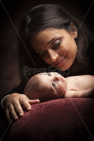 Young Attractive Ethnic Woman Holding Her Newborn Baby Under Dramatic Lighting.