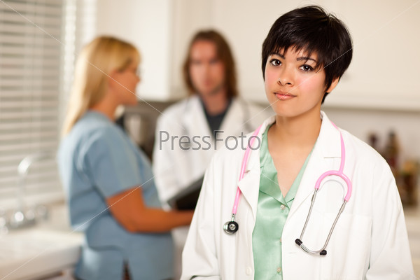 Pretty Latino Doctor Smiles at Camera as Colleagues Talk