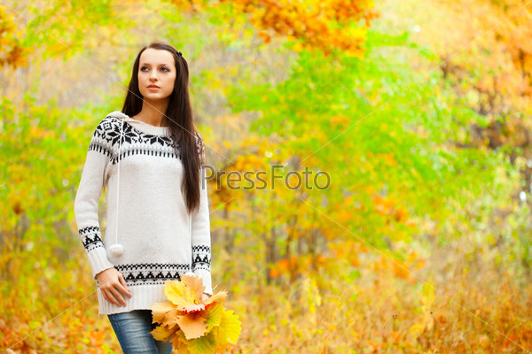brunette woman walking in autumn park  and holding leaves