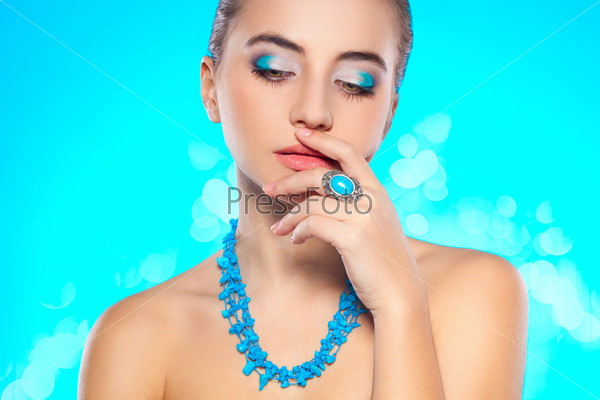 brunette woman looking down with turquoise necklace and ring on finger