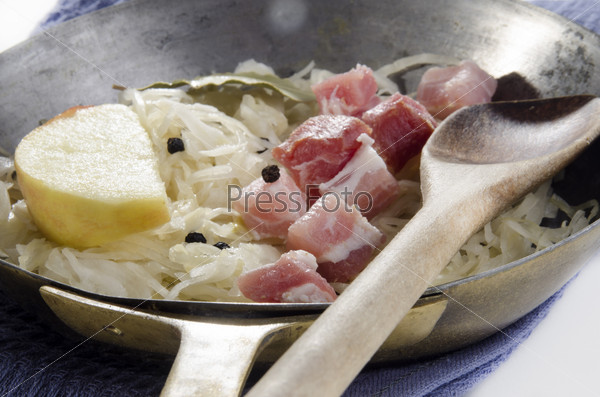 Sauerkraut with diced bacon and apple slice in a pan