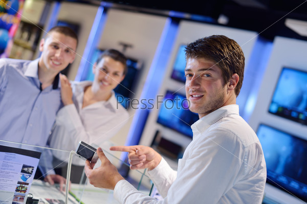 People in consumer electronics retail store looking at latest laptop, television and photo camera to buy, stock photo