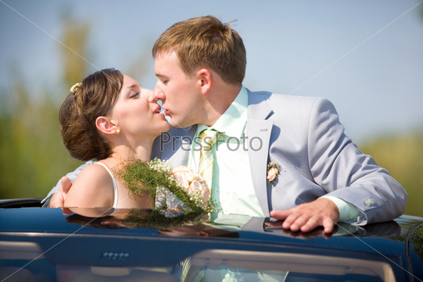 Bride and groom kissing on wedding auto