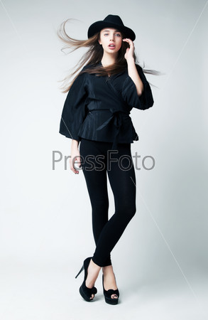 Fashionable Brunette Girl in a Black Hat with Waving Hair posing in studio. Retro Style