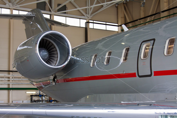 wing, the fuselage with the emergency exit and engine private plane against the hangar