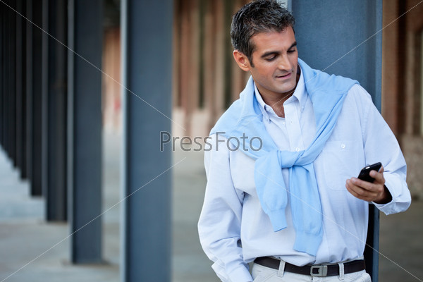 Smart casual man using cell phone with hand in pocket