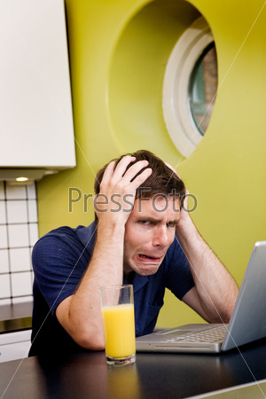 Обеспокоенный молодой человек смотрит в компьютер