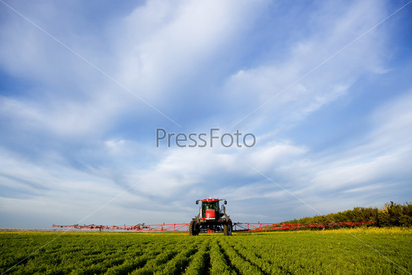 A high clearance sprayer on a field in a prairie landscape