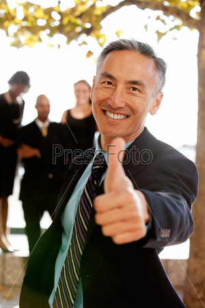 An asian looking business man with thumbs up - critical focus on eyes