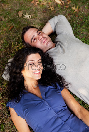 A couple day dreaming while laying on grass