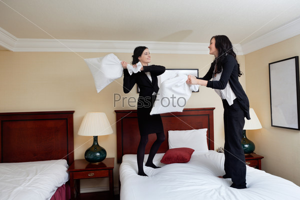 Two business women having pillow fight in a hotel room
