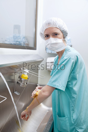 Portrait of medical woman in mask washing hands