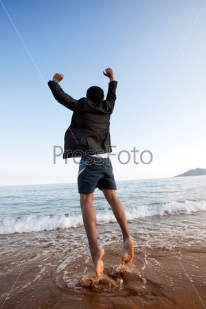 A business man jumping on the beach, freedom, success concept