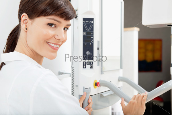 Portrait of a happy female dentist with a  Panoramic Imager X-Ray machine