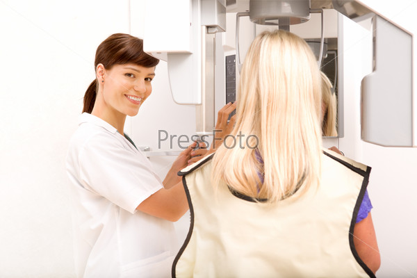 A woman taking a panoramic digital x-ray of a patients teeth