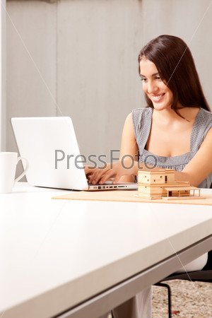 An architect working on a computer with house model on the desk