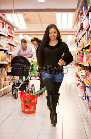 An asian woman in a grocery store with a basket