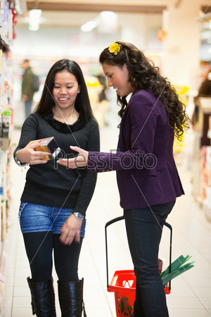 Smiling women looking at a product in a shopping store with people in the background