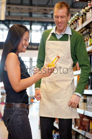 A woman receiving help from a grocery store clerk - critical focus on woman