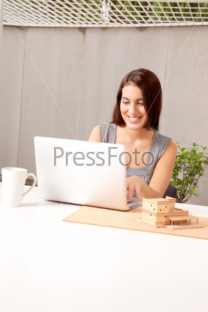 An architect using a laptop computer with a model house on the desk