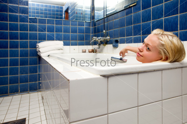 A woman in an old 20s style spa soaking in a bath tub
