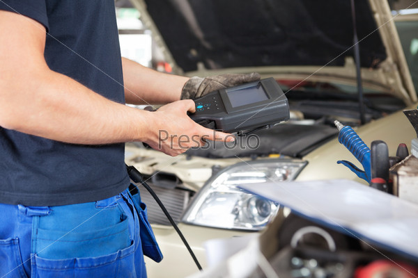 Mid section of mechanic holding a diagnostic tool