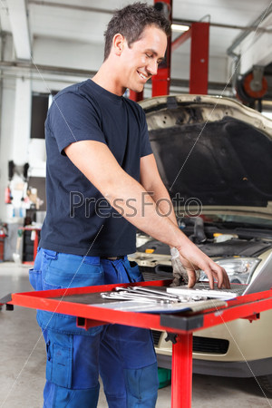Smiling young mechanic working on a laptop