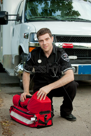 Portrait of a male paramedic in front of ambulance with portable oxygen unit