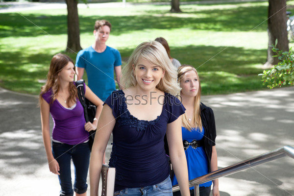 Portrait of young girl going to college with friends in background