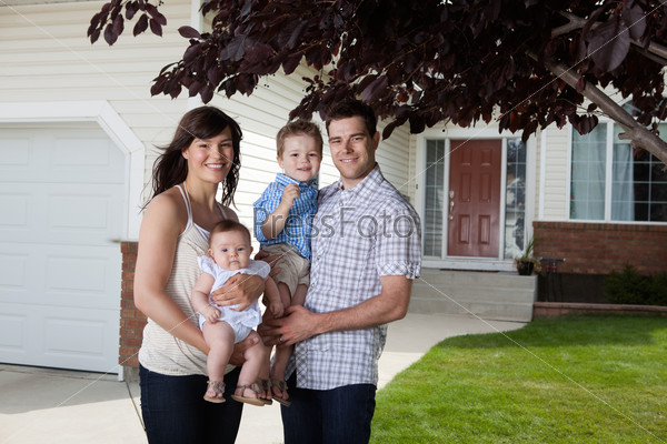 Portrait of sweet family standing in front of their house