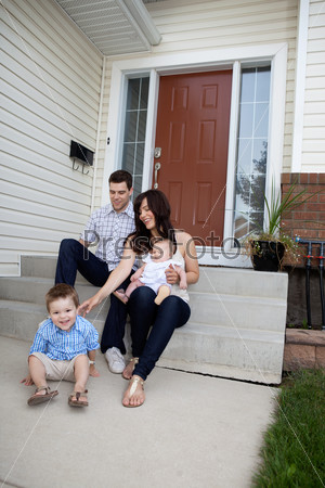 Happy family sitting on steps in front of house