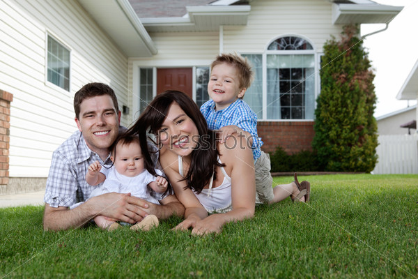 Happy couple lying down on grass with their adorable children