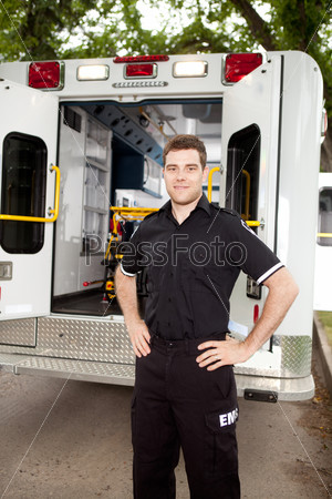 Male paramedic standing in front of ambulance in residential area