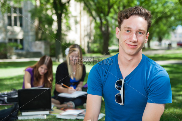 Portrait of happy college student with classmates in background