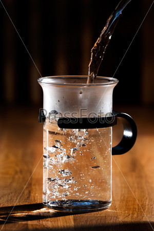 Early morning tea - glass being filled with water with strong directional  morning light