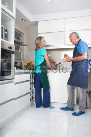 Woman working at kitchen counter while man eating salad