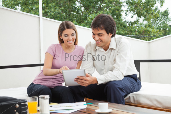 Indian male architect having discussion with female client over a digital tablet