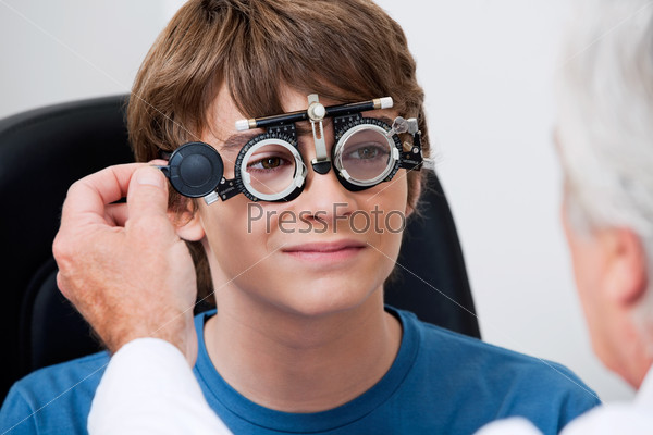 Optometrist taking eye test through trial frames at the\
clinic