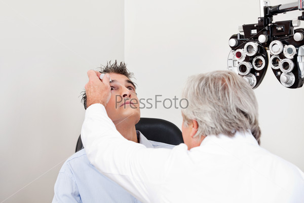Optometrist using mydriatics eye drops to numb the eyes of his patient for further tests