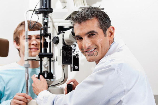 Portrait of a smiling optometrist while performing visual field test on his patient