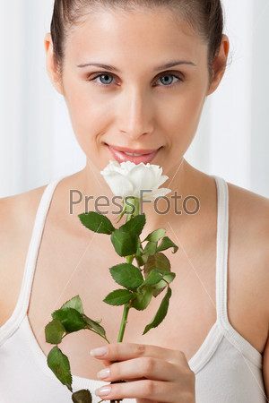 Portrait of beautiful young woman holding white rose over plain background