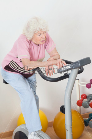 Tired Senior Woman Exercising On Bike
