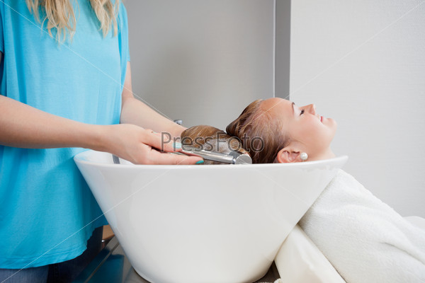 Relaxed young woman getting her washed before haircut at beauty salon