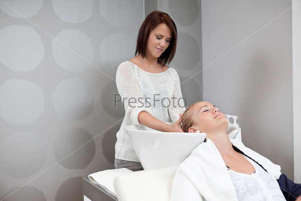 Relaxed young woman receiving head massage at hair salon