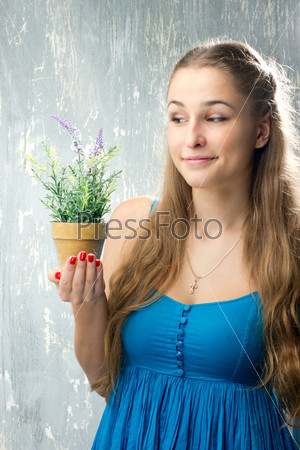 Девушка в синей одежде смотрит на цветок